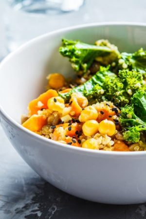 Vegan stew with chickpeas, sweet potato and kale in a white bowl.